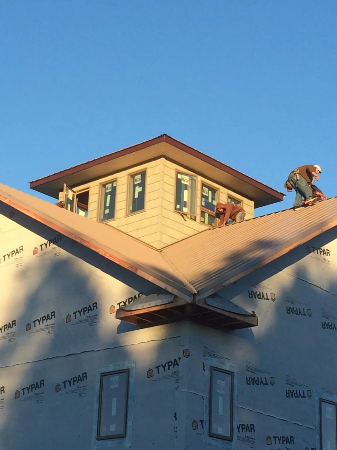 Roofers working around a rooftop cupola on a new metal roof at sunset — Roof Waterproofing in Alma by Roofing Brothers